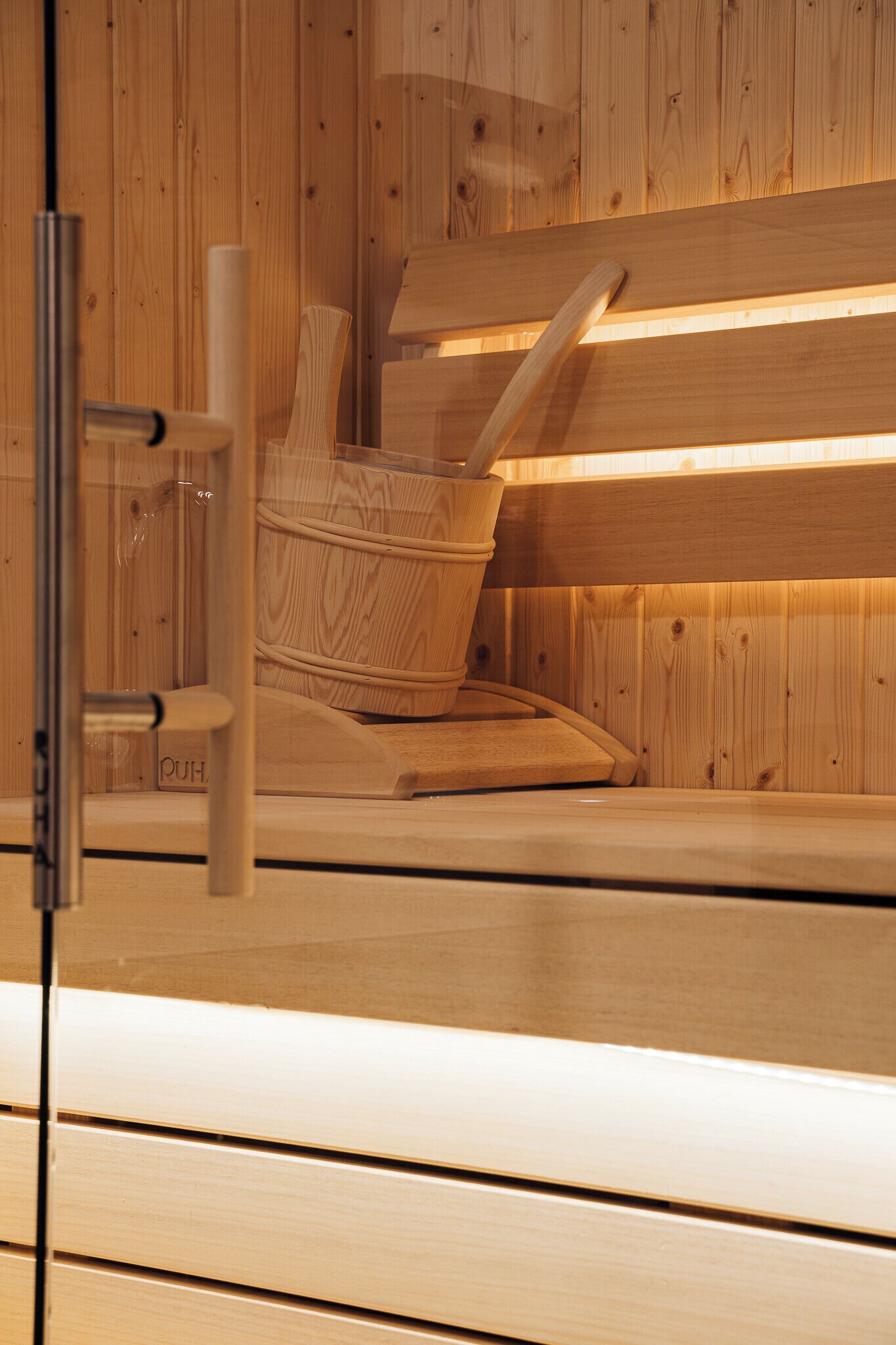 Una sauna de madera con un banco y una puerta de cristal.
