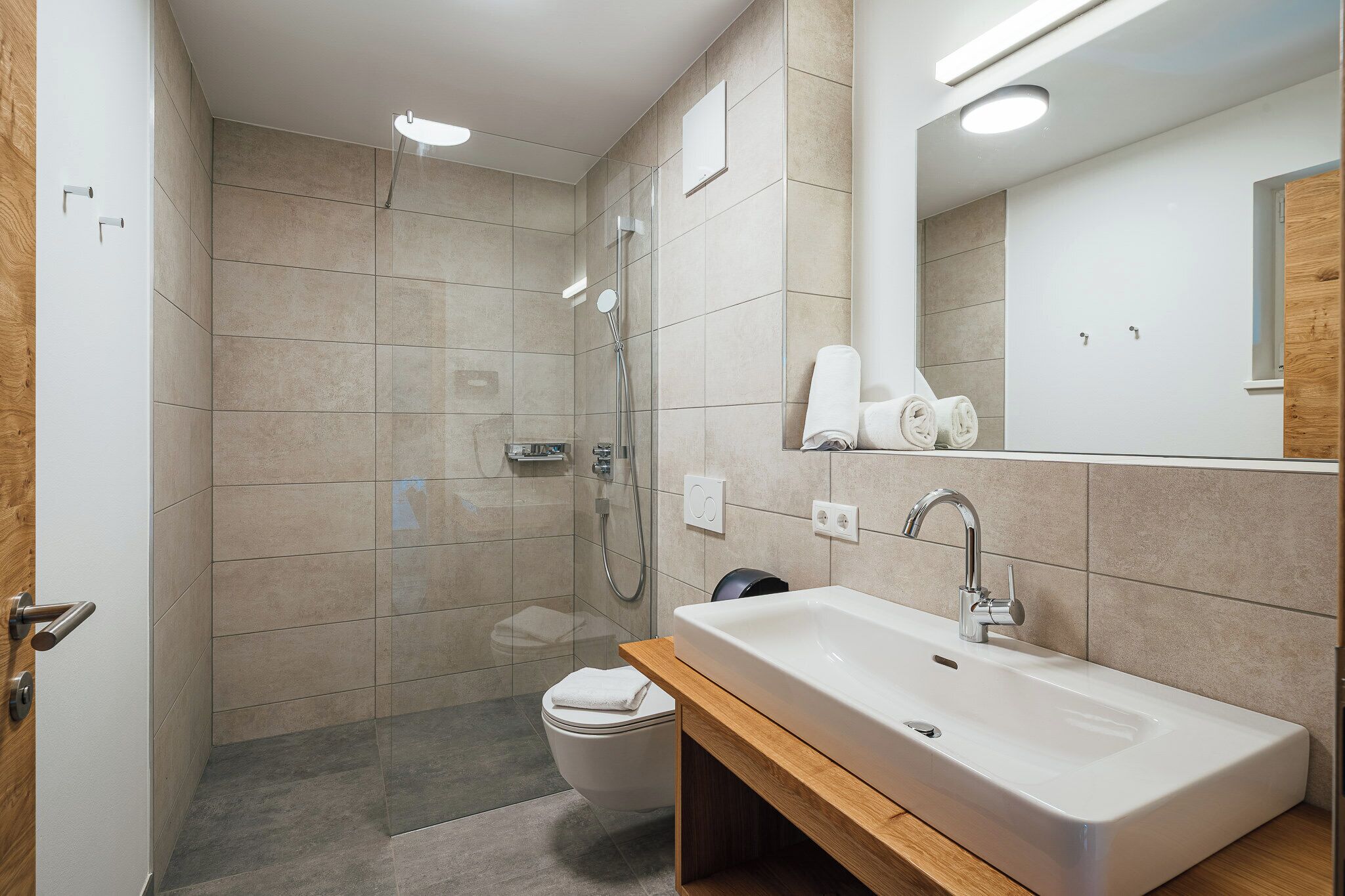 A modern bathroom with a shower, toilet, and sink.