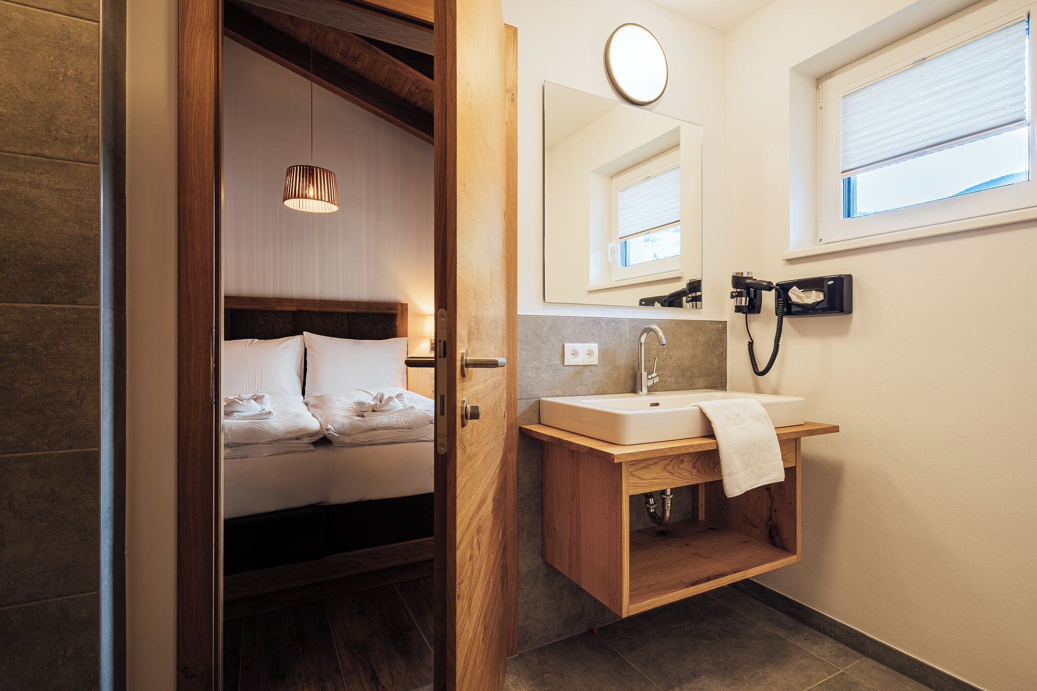 Un baño moderno con tocador de madera, un espejo grande y una lámpara de noche.