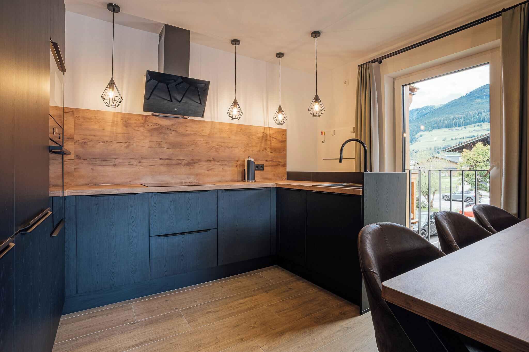 Een moderne keuken met houten details, hanglampen en uitzicht op de omgeving.