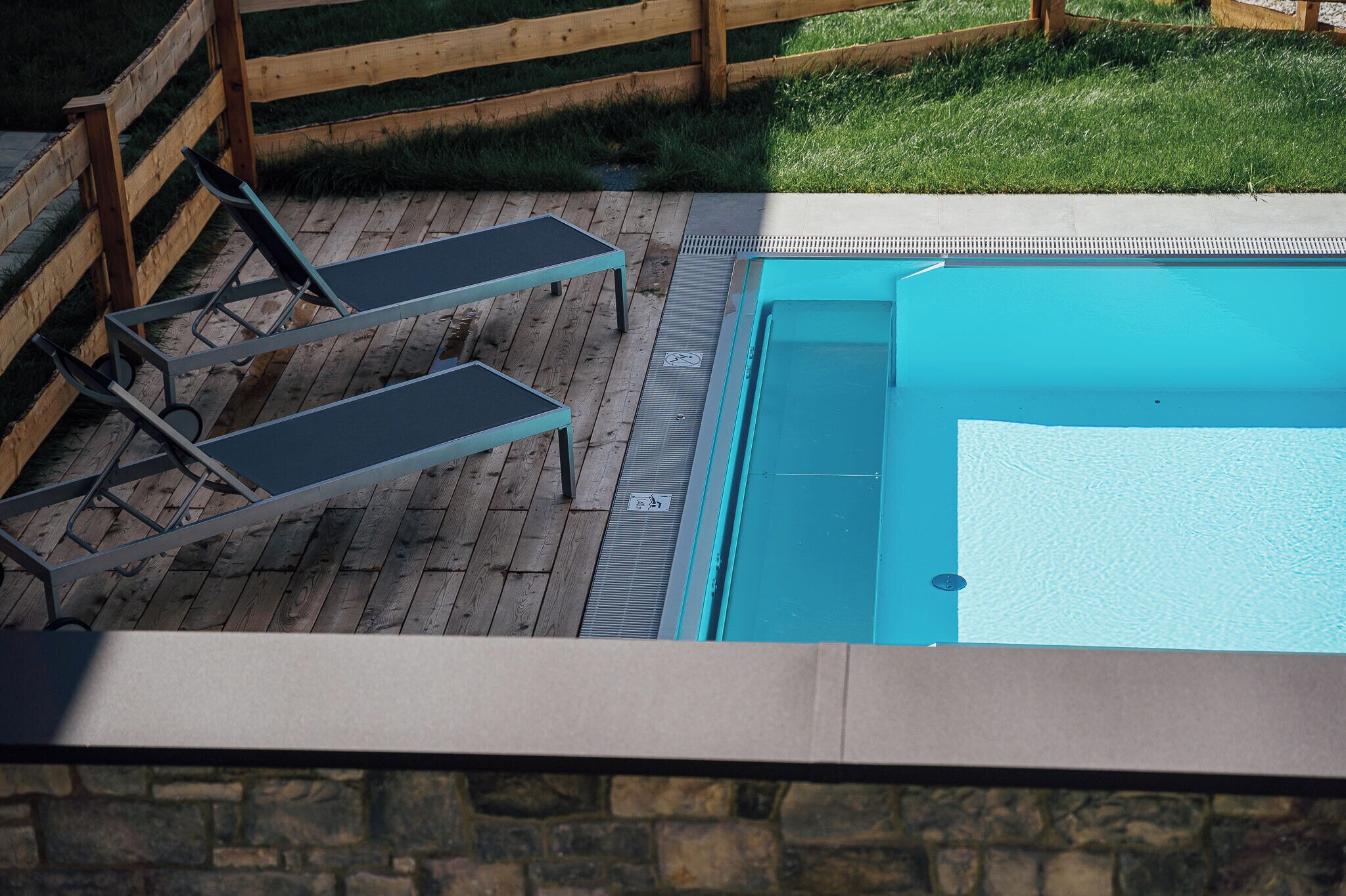 Una piscina con dos tumbonas y una terraza de madera.