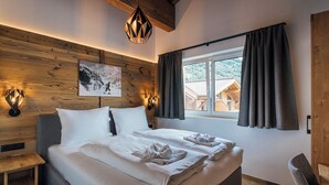 A bedroom with a large bed, wooden headboard, and a window with curtains. - Der Kehlbachwirt by Monteviva (Niedernsill)