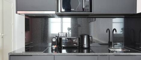 A modern kitchen with a built-in microwave, coffee maker, and toaster.