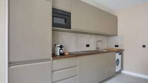 Una cocina moderna con electrodomésticos integrados, un lavamanos y una lavadora.
