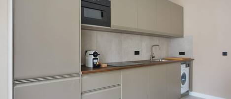 A modern kitchen with built-in appliances, a sink, and a washing machine.