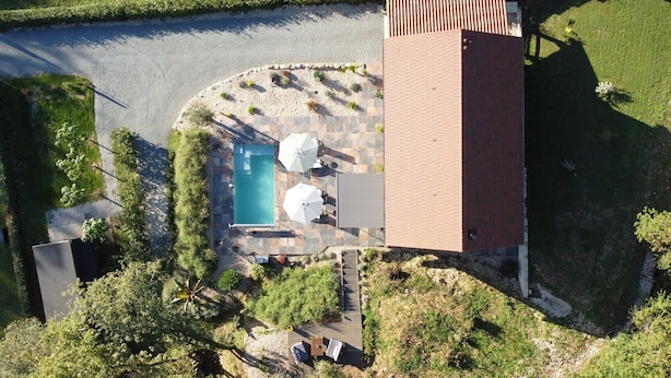 An aerial view of a property with a swimming pool, outdoor seating, and a tall brick structure. - Exceptional stay in Périgord : Tobacco drying house, Heated swimming pool (Marnac)