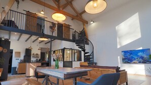 Une cuisine spacieuse avec des meubles en bois, un coin repas avec des bancs, un escalier et un grand aquarium mural.