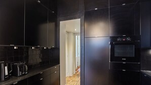 Uma cozinha moderna com armários pretos, um forno Bosch e uma cafeteira.