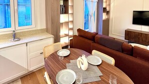 Una sala de estar moderna con una mesa de comedor de madera, un sofá y un televisor montado en la pared.