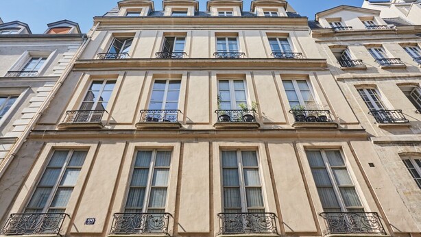 Un immeuble à plusieurs étages doté de grandes fenêtres et de balcons.