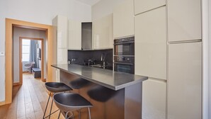 Une cuisine moderne dotée d’un grand îlot central, d’appareils électroménagers en acier inoxydable et d’un plancher en bois.