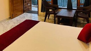 Ein Zimmer mit Bett, Tisch und Stühlen, ein Balkon mit Bergblick und Holzbalken an der Decke.
