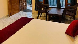 Ein Zimmer mit einem Bett, zwei Stühlen, einem Tisch und Blick auf die Berge durch große Fenster.