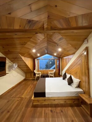 Een gezellig houten slaapkamer met een bed, een kleine tafel, twee stoelen en een raam met uitzicht.