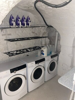 Efficient laundry area with washing machine, dryer, and ironing boards.