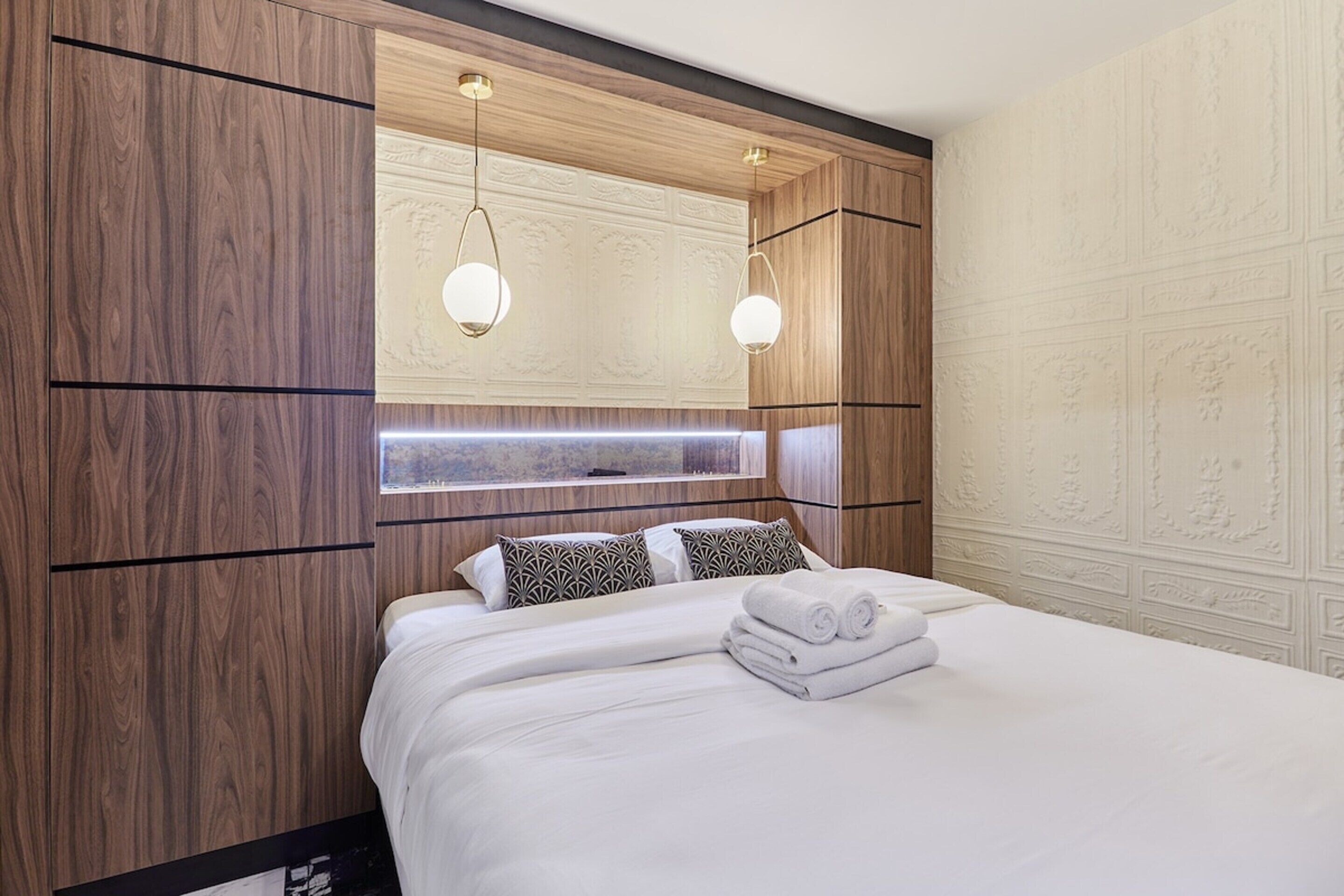 Habitación de hotel con una cama grande, paneles de madera y un techo decorativo.