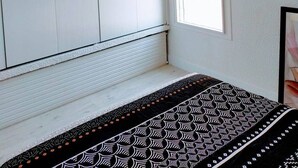 A bedroom with a large wardrobe, a window, and a patterned bedspread.