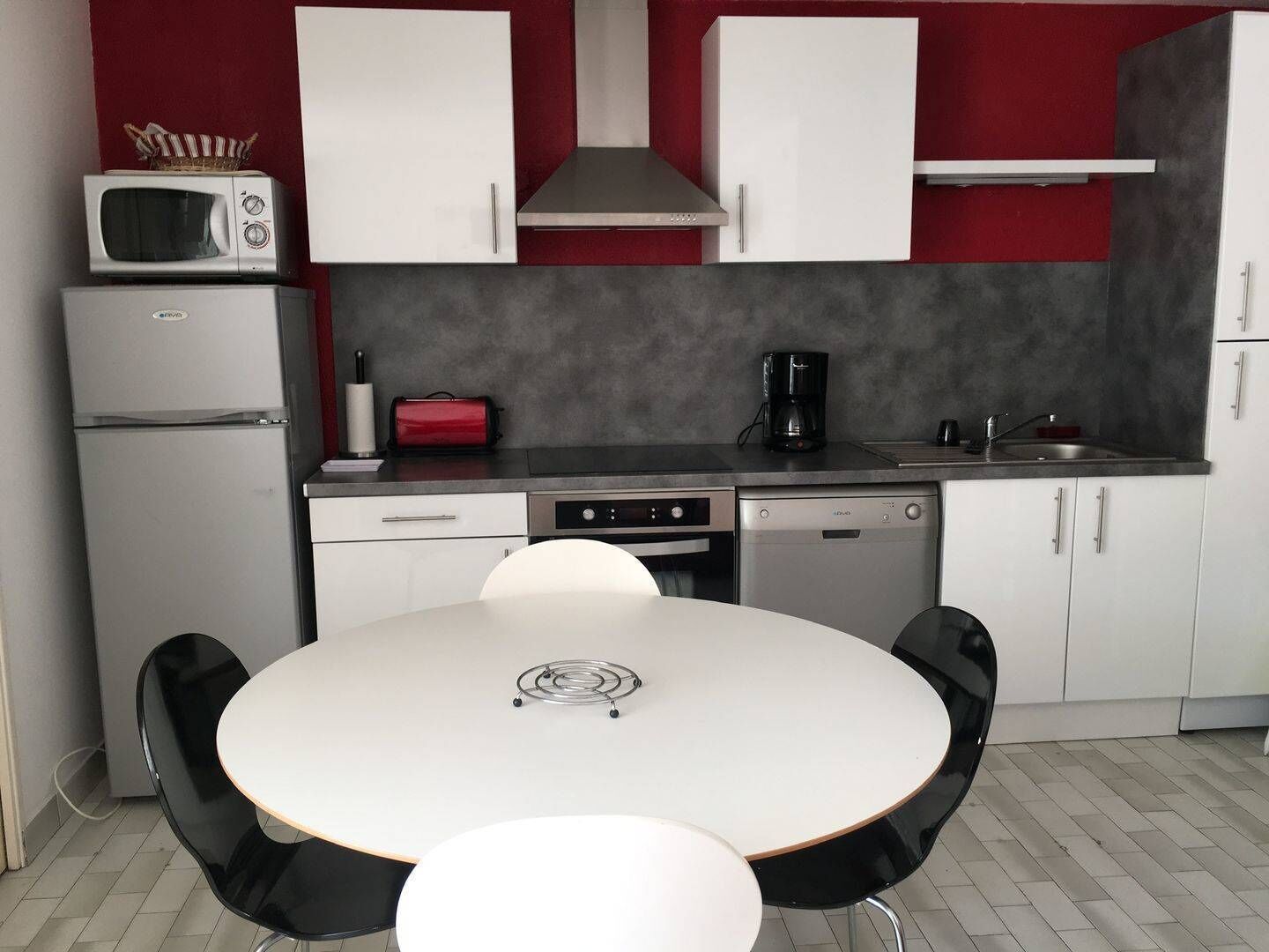 A compact kitchen with white cabinets, a microwave, a coffee maker, and a dishwasher.