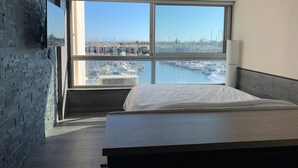 A modern hotel room with a large window offering a marina view.