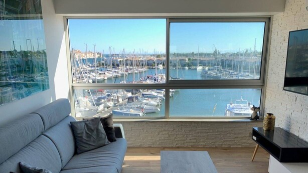 A modern living room with a large window overlooking a marina.