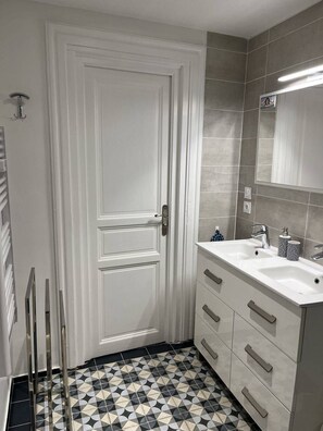 Bathroom features a white sink, large mirror, and geometric-patterned floor.