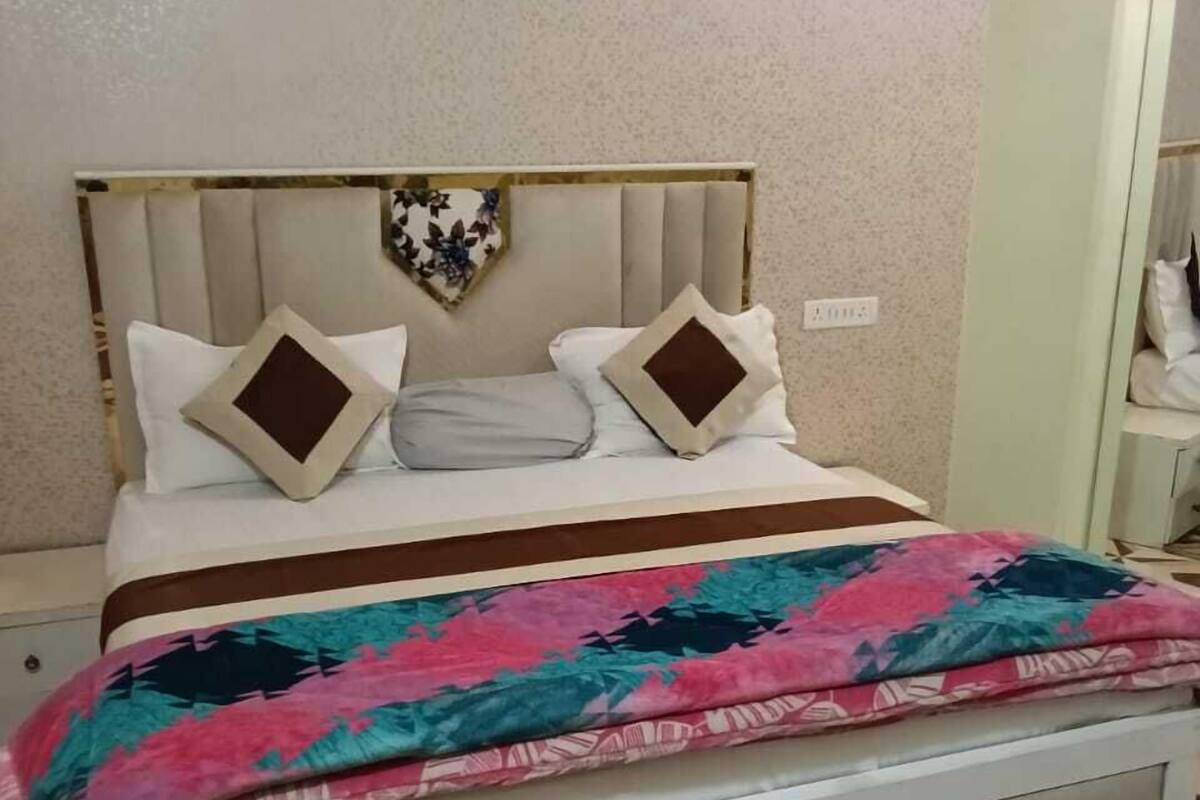 Un llit amb un estovat estampat, un capçal amb elements decoratius i una meseta de nit amb una làmpada.