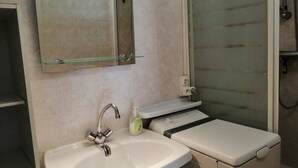 A bathroom with a sink, mirror, and shower. - 2 Bed apartment ground floor / Mont St Martin (CAP D AGDE)