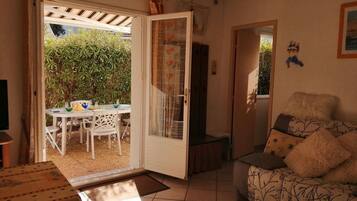Una habitación con zona de comedor, sofá y puerta que da al exterior.