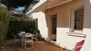 A patio with a table and chairs, a covered area, and a window with a view of the sky. - 2 Bed apartment ground floor / Mont St Martin (CAP D AGDE)