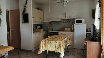 Una cocina funcional con una mesa de comedor, ventilador de techo y electrodomésticos básicos.