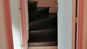 A narrow stairway with a handrail, leading to a landing with a small window.