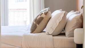 A bed with white bedding and multiple pillows, a wooden headboard, and a wooden floor. - Acropolis View 3-bdrm With Rooftop Garden Jacuzzi (Athens)