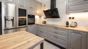 A modern kitchen with stainless steel appliances, a wooden countertop, and grey cabinetry. - Acropolis View 3-bdrm With Rooftop Garden Jacuzzi (Athens)