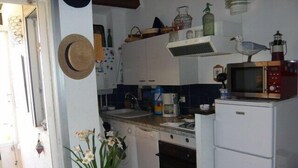A compact kitchen with white cabinets, a microwave, a sink, and a stove. There is a potted plant with white flowers on the counter. - 1 bed + gallery apartment / Ile des Marinas (CAP D'AGDE)