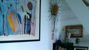 A tan sofa in a room with a painting, a sun decoration, and a framed check on the wall. - 1 bed + gallery apartment / Ile des Marinas (CAP D'AGDE)