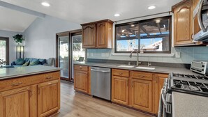A modern kitchen with wooden cabinets, a dishwasher, a sink, and a stove. - 3-bedroom Artist Oasis in the HeART of Las Vegas (Las Vegas)