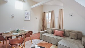 A dining area with a round table set for four, a sofa, and a window with curtains. - Superb Flat Ave Montaigne With Eiffel Tower View (Paris)