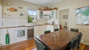 A kitchen with wooden cabinets, a microwave, and a dining table with chairs. - Welcome to Waterfront Views (Gympie)