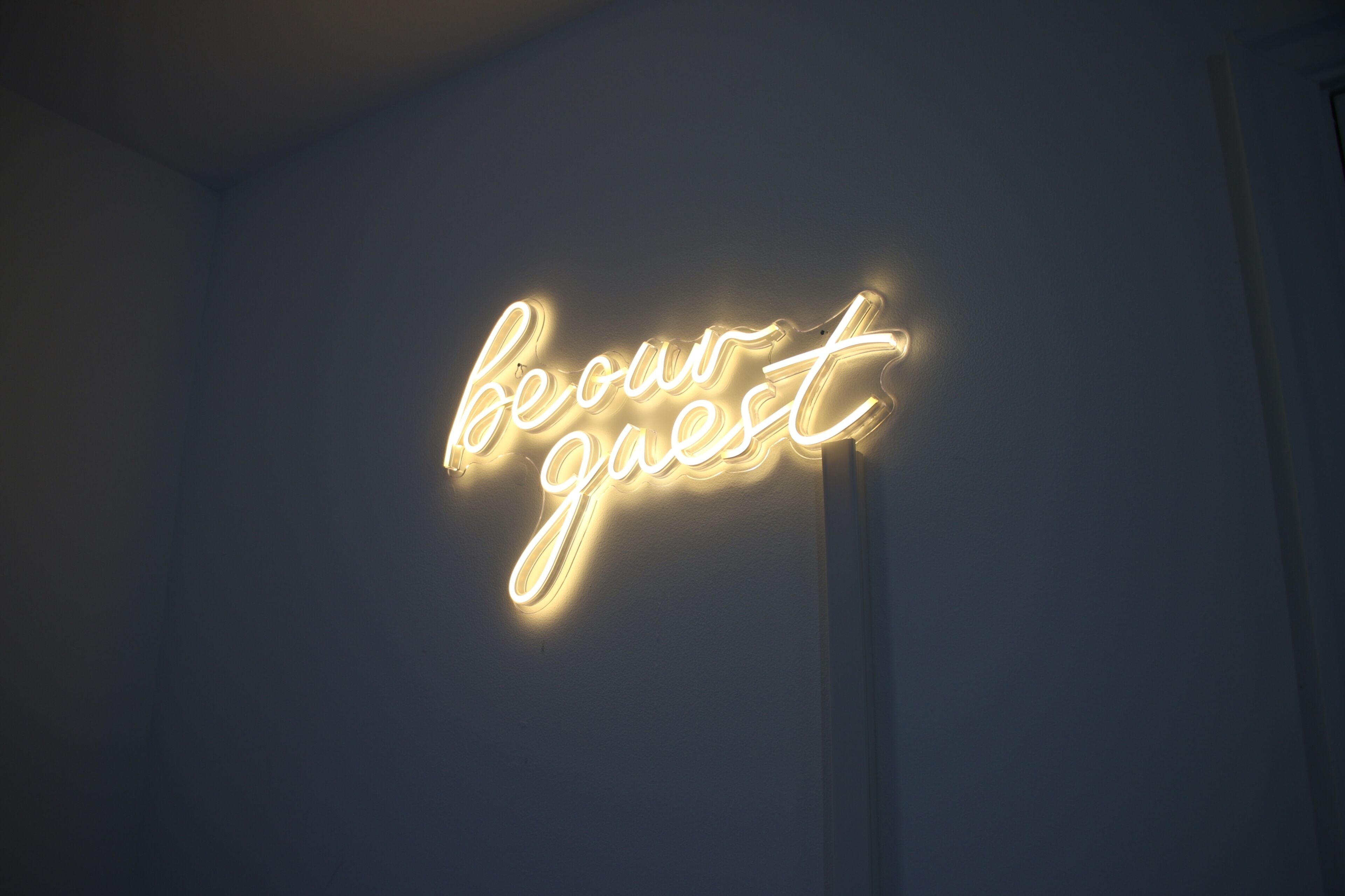 Une enseigne au néon avec les mots « soyez les bienvenus » sur un mur.