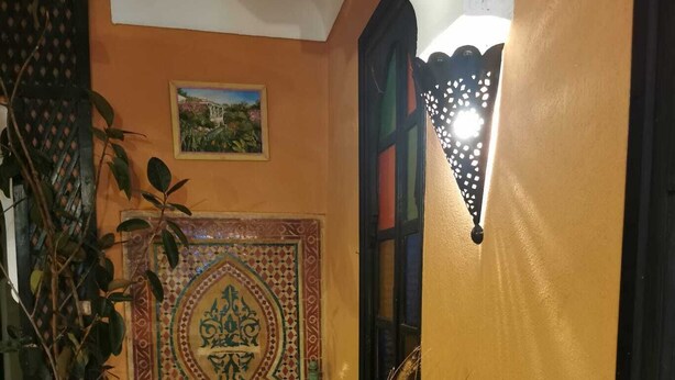 Een binnentuin met een betegelde muur, plantenbakken en een decoratief tegelpatroon.