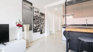 Una cocina moderna con encimera de madera, taburetes negros y un banco blanco.