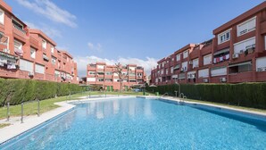 Una piscina rodeada de edificios de apartamentos con balcones y unidades de aire acondicionado.
