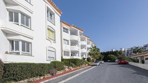 A row of white buildings with balconies, a gravel driveway, and parked cars. - Arte De Luz - Apartment In Calahonda-chaparral (Mijas (mÁlaga), Málaga)