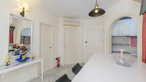 A modern kitchen with white cabinets, a dining table, and a mirror above the counter. - Arte De Luz - Apartment In Calahonda-chaparral (Mijas (mÁlaga), Málaga)