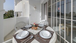 A dining area with a table set for four, white chairs, and a view through a glass door. - Arte De Luz - Apartment In Calahonda-chaparral (Mijas (mÁlaga), Málaga)