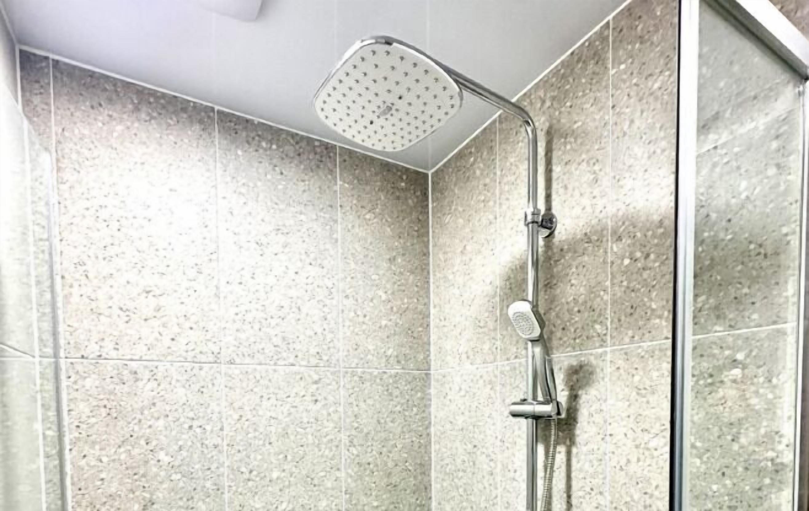Eine Dusche mit Handbrause und Armaturen an der Wand.