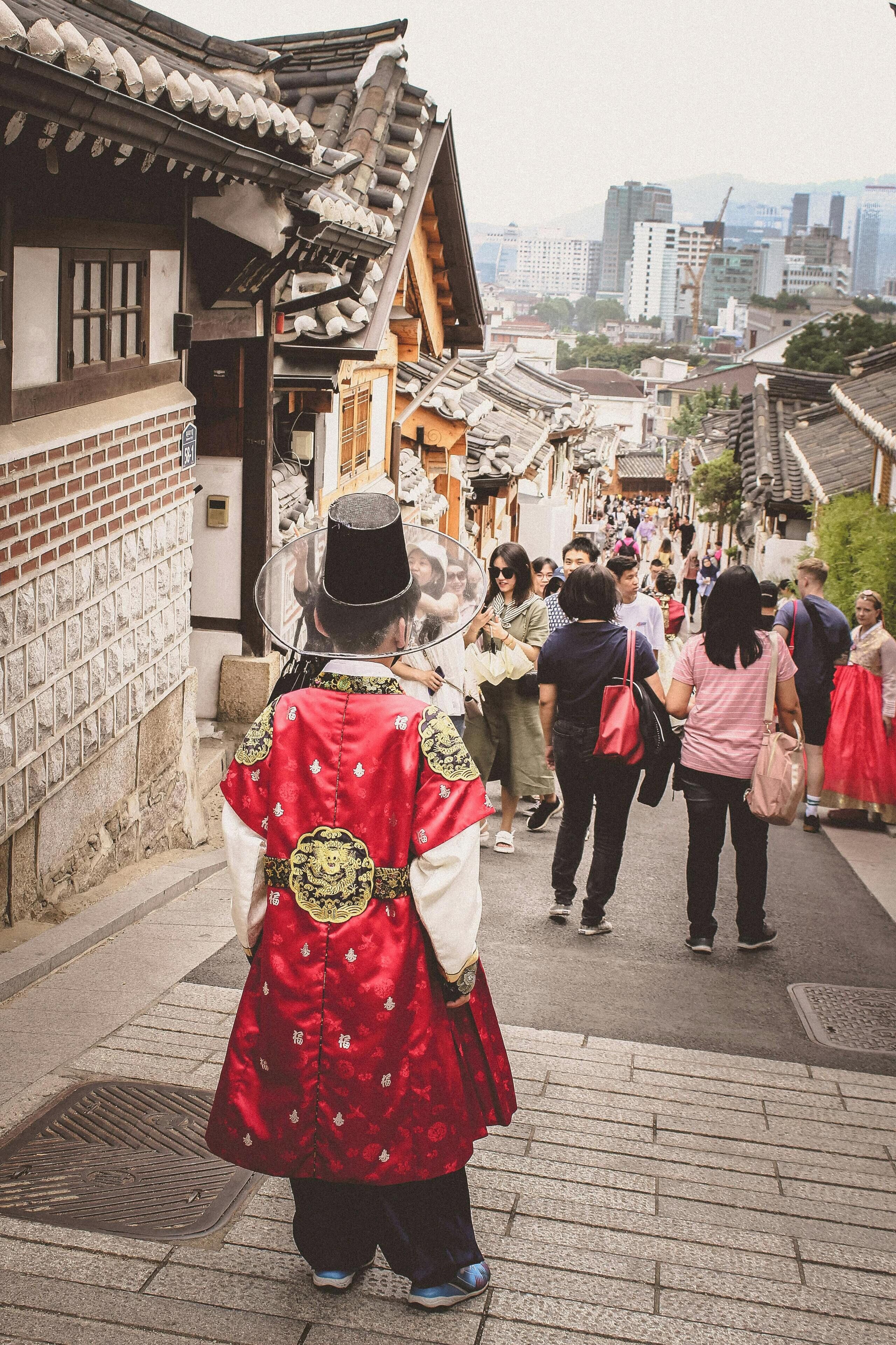 A traditional Japanese street with a person in a red kimono walking down the path.
