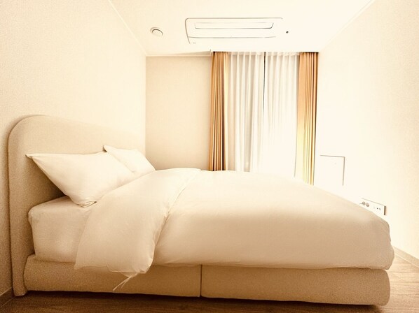 A modern bedroom with a bed, curtains, and a wall-mounted air conditioner. - The November Stay Guri (Guri)