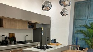 Eine moderne Küche mit Kochinsel, Holzstühlen und Pendelleuchten.