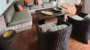 A cozy living area with a stone wall, a sofa set, a coffee table, wicker chairs, and a ceiling fan. - w* |Marvelous 3BR House with pool in Cartagena (Cartagena de Indias)